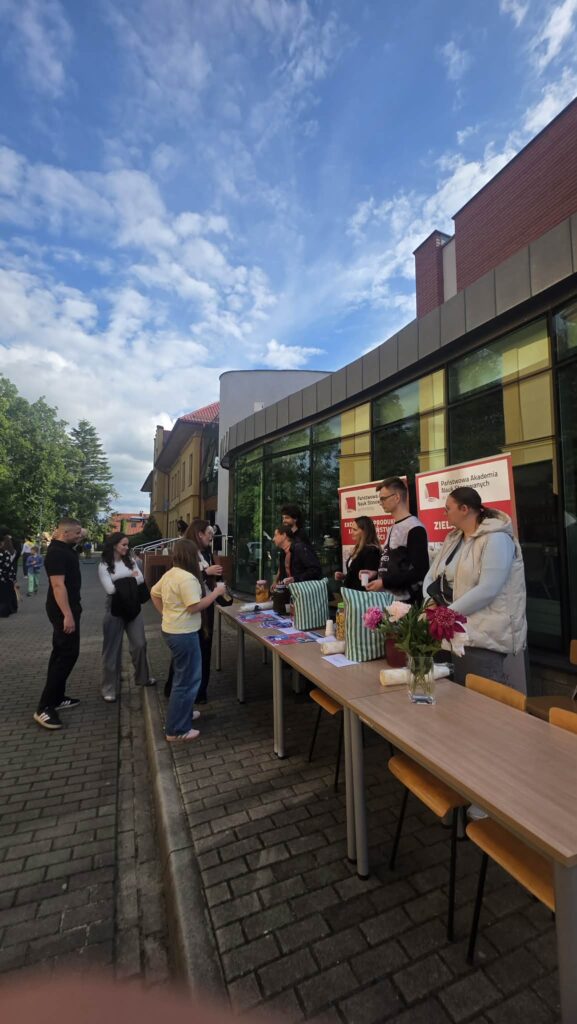 Studenci stoją na tle banerów kierunku EPIBZ i Zielarstwo, przed nimi na stołach napoje przygotowane dl uczestników część już się częstuje
