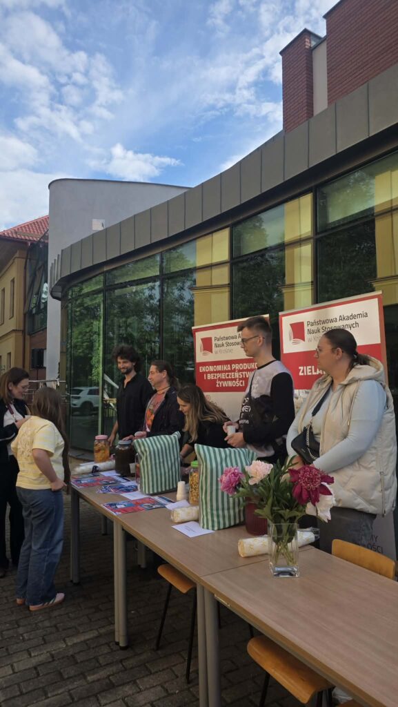 Studenci stoją na tle banerów kierunku EPIBZ i Zielarstwo, przed nimi na stołach napoje przygotowane dl uczestników część już się częstuje