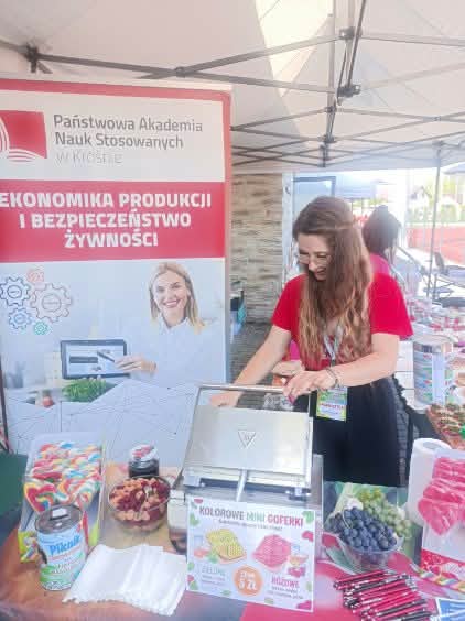 Studentka piecze gofry, na stoliku stole kolorowe lizaki, z tyłu baner kierunku EPIBŻ