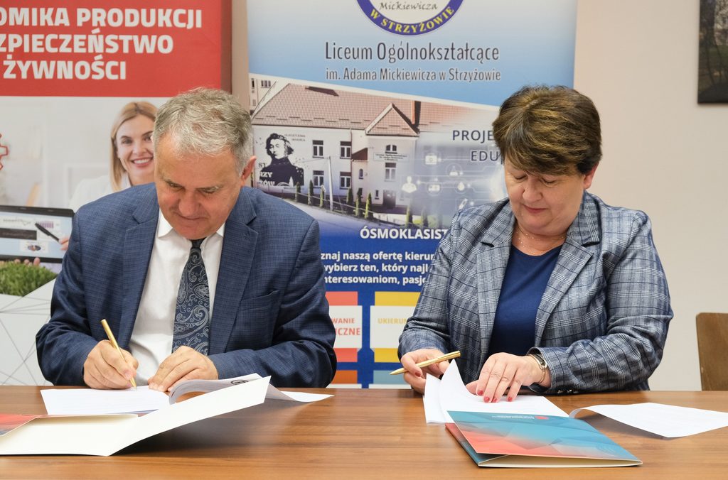 Uczestnicy podpisania porozumienia siedzą , z tyłu baner kierunku EPIBŻ i szkoły, Rektor i Dyrektor szkoły podpisują porozumienie.