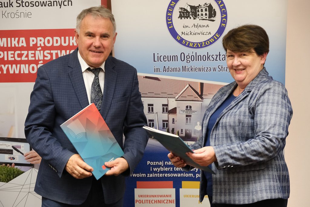 z tyłu baner kierunku EPIBŻ i szkoły, Rektor i Dyrektor szkoły stoją z podpisanymi porozumieniami