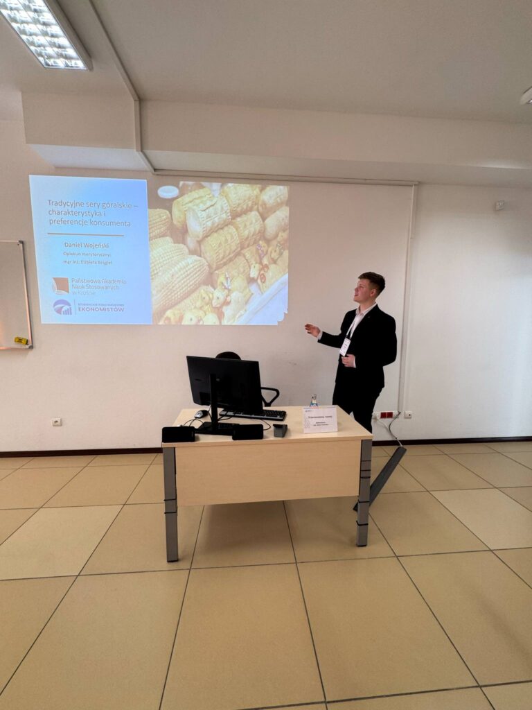 Student Daniel podczas wystąpienia, biurko, prezentacja na ekranie