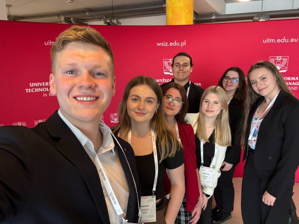 selfy wszystkich studentów z koła i organizatorów na tle czerwonej ścianki uczelni WSIZ