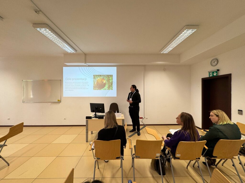 Student Szymon podczas wystąpienia, biurko, prezentacja na ekranie