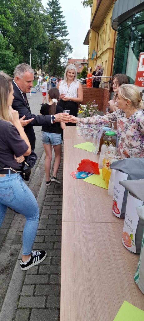 uczestnicy przy stoisku sięgają po napoje