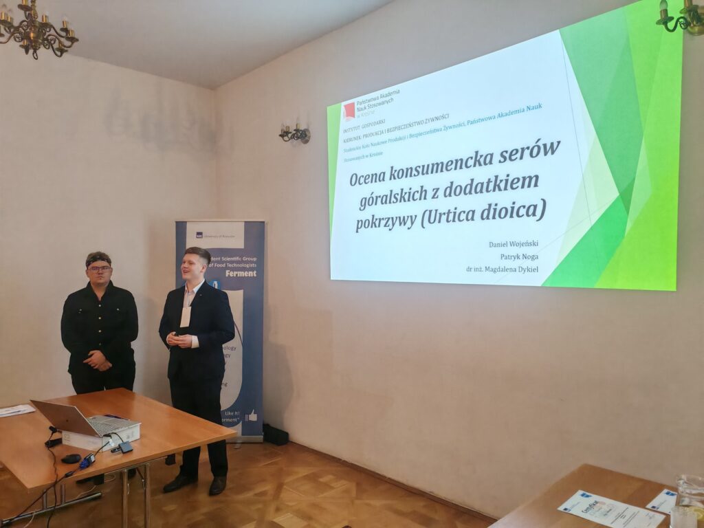 Studenci Daniel Wojeński, Patryk Noga referują z boku slajd z prezentacją