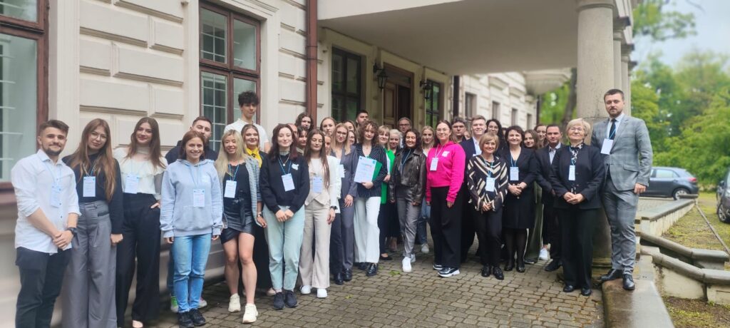Grupa wszystkich uczestników konferencji na tle budynku konferencyjnego
