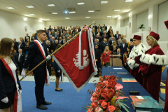 Poczet sztandarowy przy władzach uczelni na auli podczas uroczystości