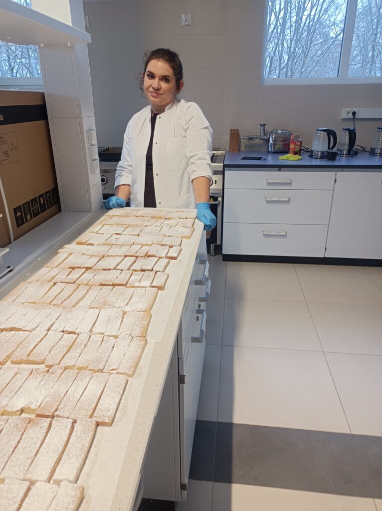 Studentka przy stole w laboratorium i cały blat upieczonych ciasteczek