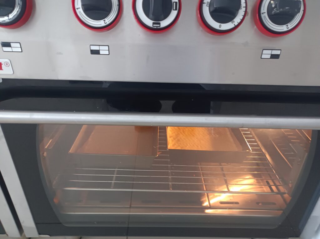 Piekarnik , w nim blaszki z piekącym się ciastem