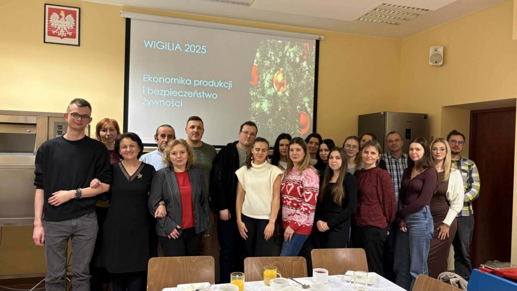 Studenci z opiekunami razem na tle ekranu z napisem Wigilia kierunkiem i motywem choinki