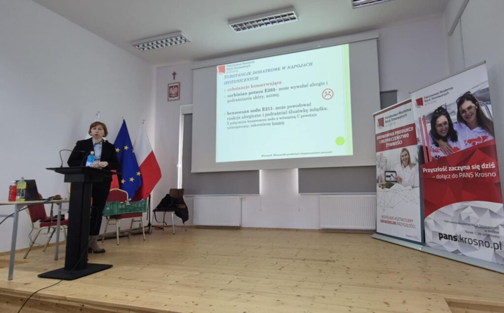 Scena, slajd z wykładem po prawej banery uczelni i kierunku, prowadząca głosi wykład