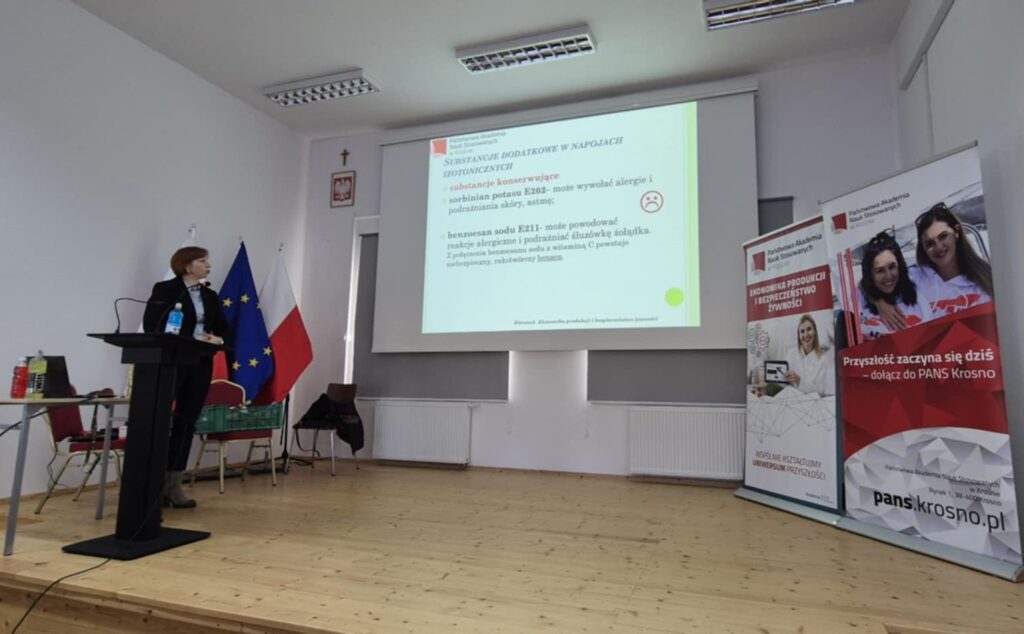 Scena, slajd z wykładem po prawej banery uczelni i kierunku, prowadząca głosi wykład