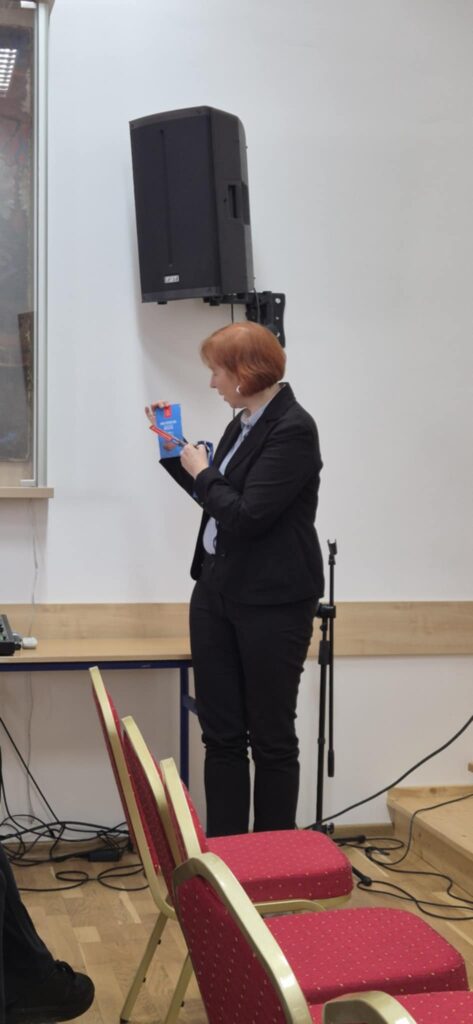 Scena, slajd z wykładem po prawej banery uczelni i kierunku, prowadząca głosi wykład pokazuje przykładowy produkt