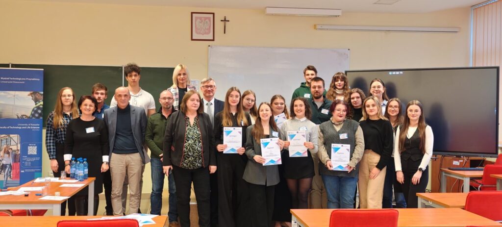 Wszyscy uczestnicy na zdjęciu grupowym w sali na tle tablic