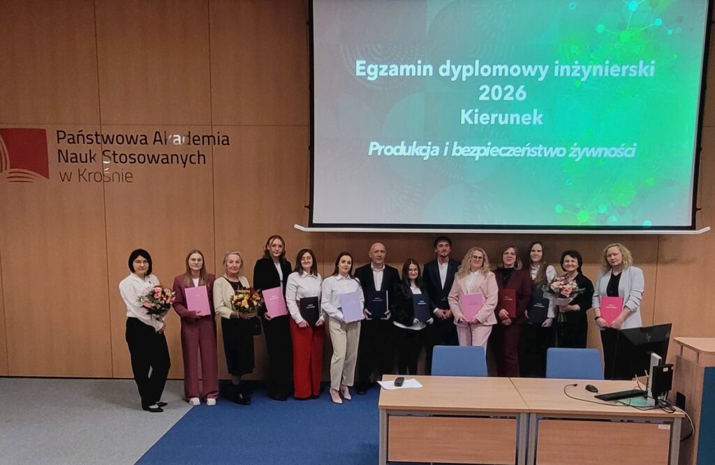 Wszyscy studenci z promotorami  w auli na tle ekranu z tytułem egzamin dyplomowy inżynierski kierunku PIBŻ