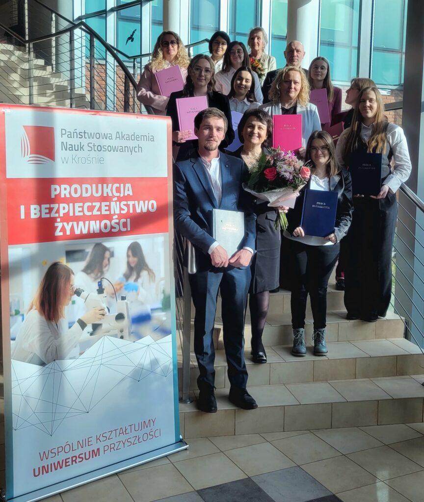 Wszyscy studenci z promotorami na stoją na schodach w holu głównym, obok baner kierunku PIBZ 