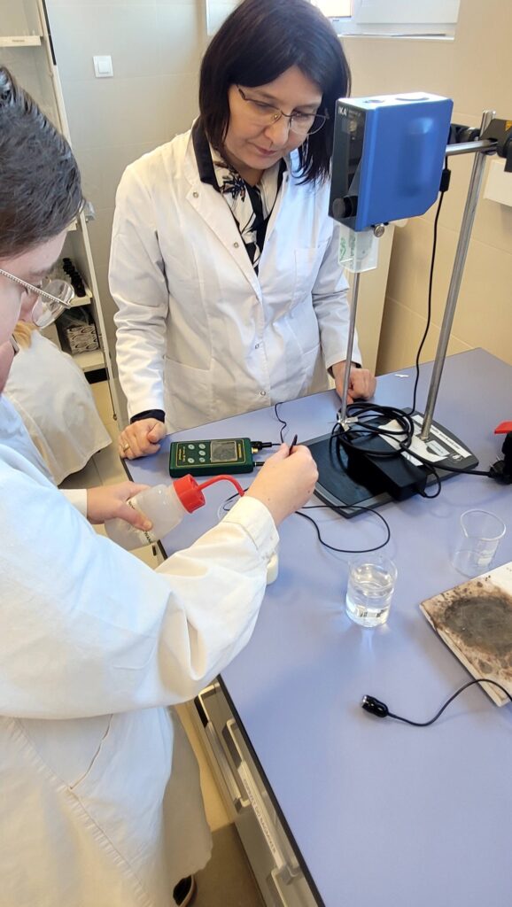 Uczennica po opieką prowadzącej bada pH mleka