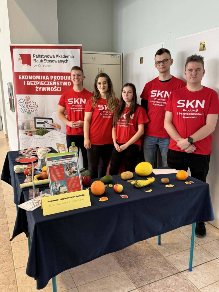 Studenci z kła SKN PIBŻ, baner za nimi, przed nimi stół z owocami, ulotkami