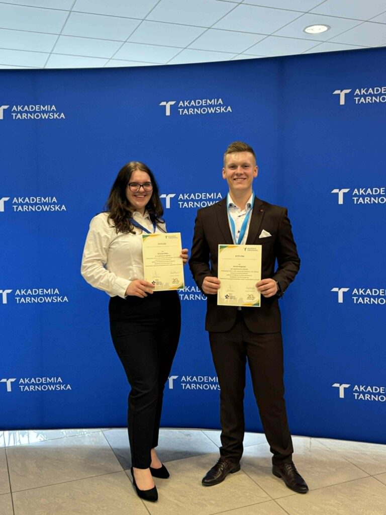 Studenci -dwoje stoją z dyplomami na tle ścianki Akademia Tarnowska