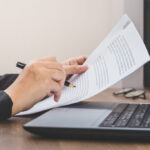 Business woman checking the paper, working with laptop and documents on her desk, business concept