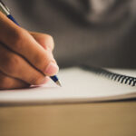Man hand with pen writing on notebook.